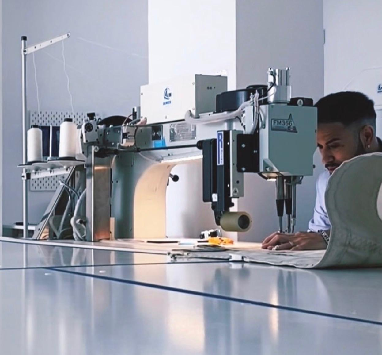 Sailcloth passing under an industrial sewing machine needle in a sailmaking workshop