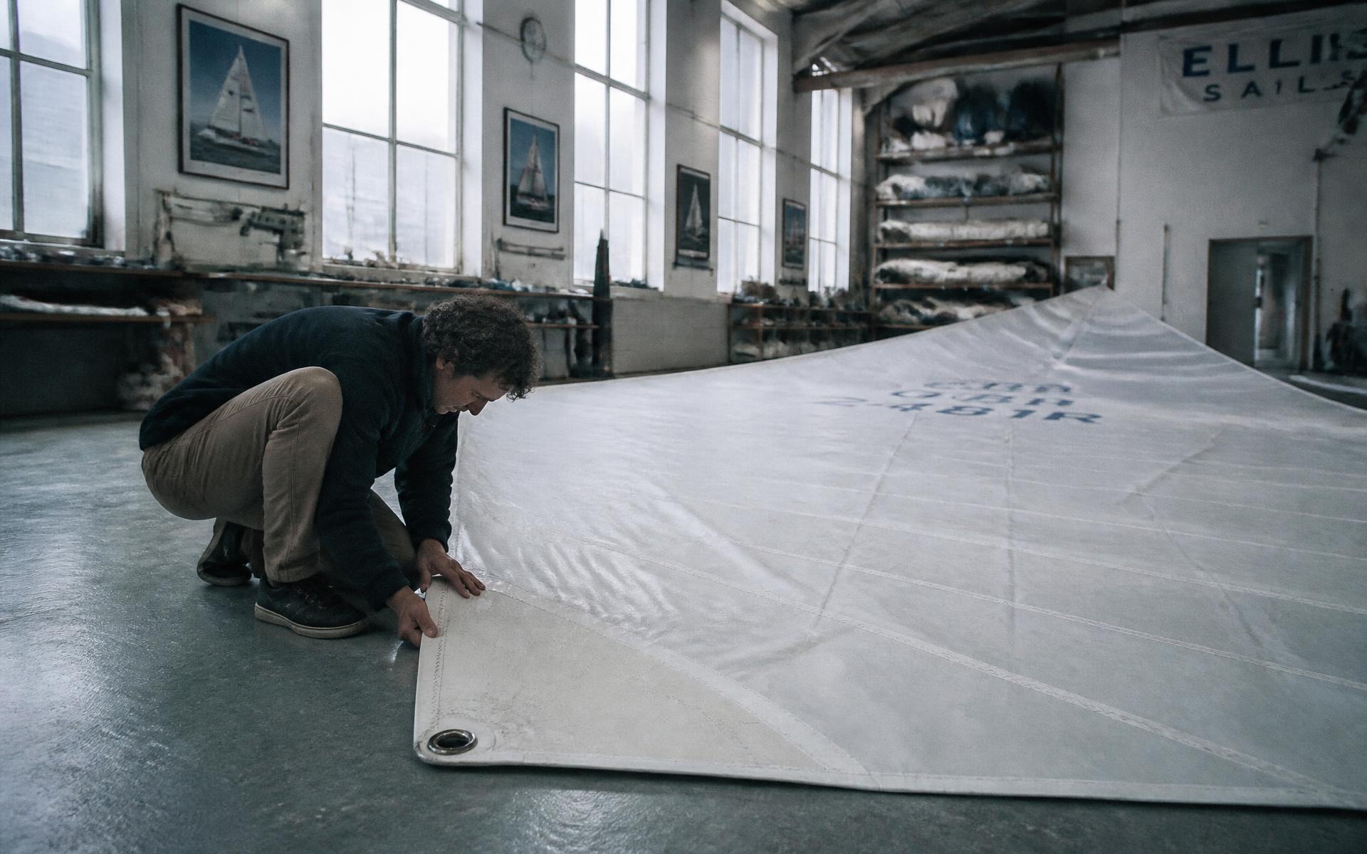 A new white sail with a reinforced corner ring laid out in the workshop